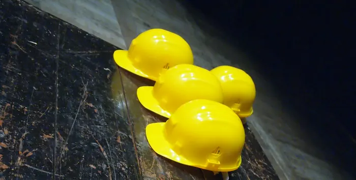 Yellow hard hats lined up on a worn timber bench