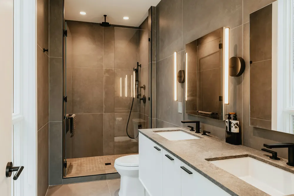 Bathroom with a frameless glass shower, large stone-look tiles and a double vanity