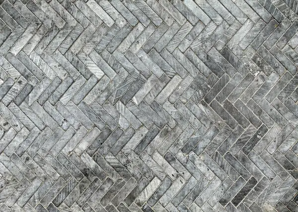 Grey marble tiles laid in a tight herringbone pattern